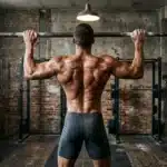 Homme musclé torse nu à la barre fixe en gym