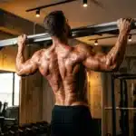 Homme musclé effectuant une traction à la barre en salle de gym