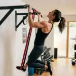 Femme effectuant des tractions assistées avec bande élastique rouge