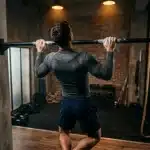 Homme effectuant traction à la barre en salle musculation