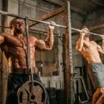 Deux hommes musclés font des tractions à la barre en gym