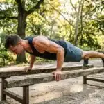 Homme musclé effectue une planche sur un banc en bois