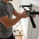 Homme installant une barre de traction noire au mur