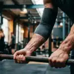 Homme musclé tenant une barre de musculation en salle