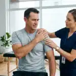 Physiothérapeute examinant l'épaule d'un patient en cabinet