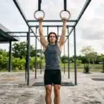 Homme musclé suspendu aux anneaux de gymnaste en plein air