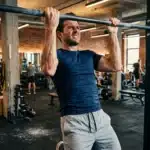 Homme effectuant des tractions à la barre en gym