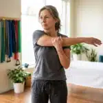 Femme en tenue de sport faisant un étirement du bras en clinique