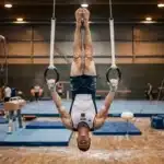 Gymnaste suspendu inversé aux anneaux dans un gymnase