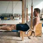 Athlète masculin effectuant exercice aux anneaux de gymnastique