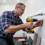 Homme avec perceuse fixe barre de douche salle bain